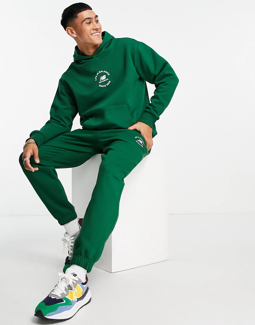 New Balance – Kapuzenpullover in Grün mit „Life in Balance“-Print günstig online kaufen