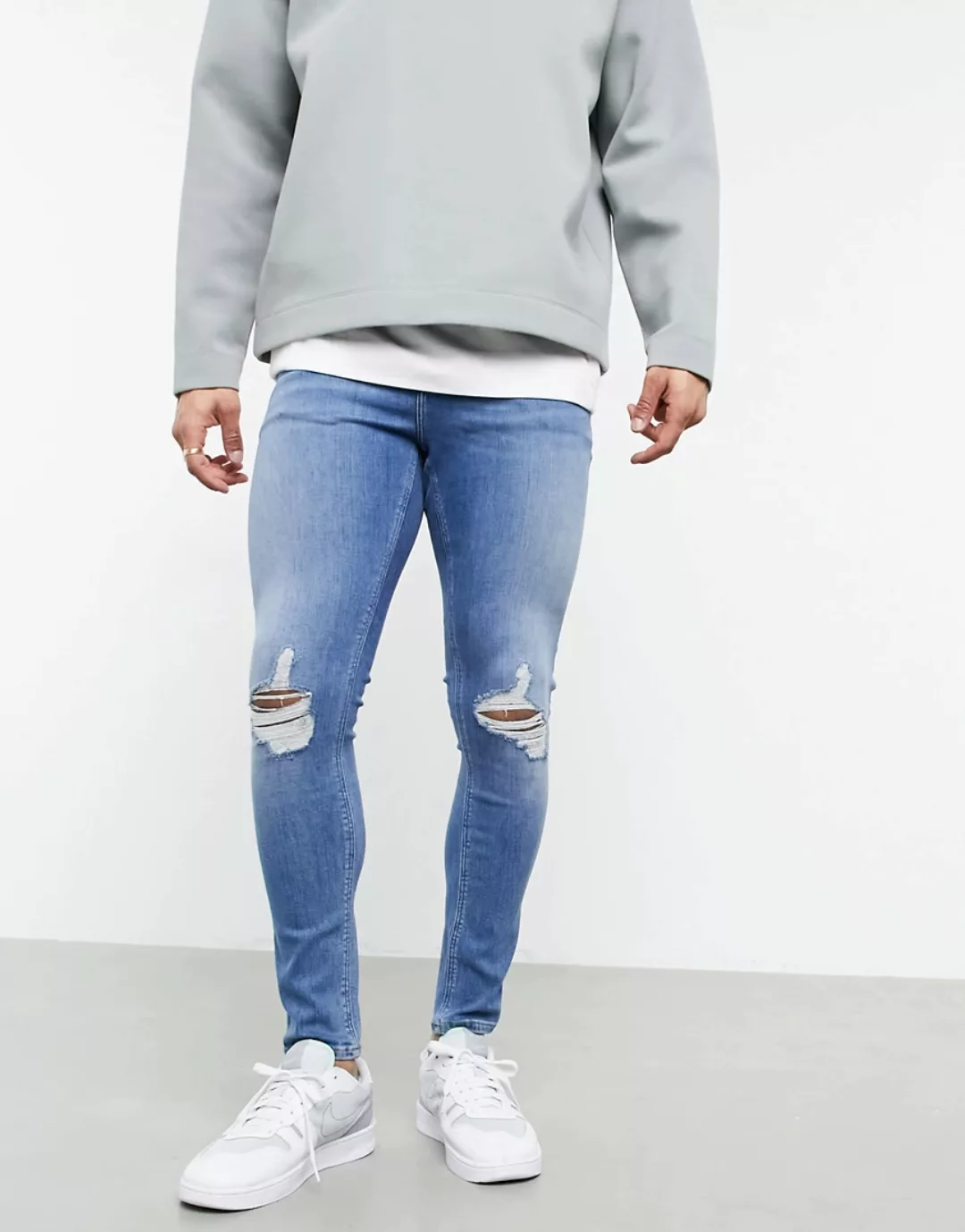 ASOS DESIGN – Sprayon-Jeans mit Powerstretch, Knierissen und mittelblauer V günstig online kaufen