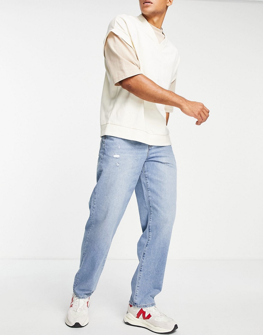 ASOS DESIGN – Baggy-Jeans in mittelblauer Waschung mit Abschürfungen günstig online kaufen